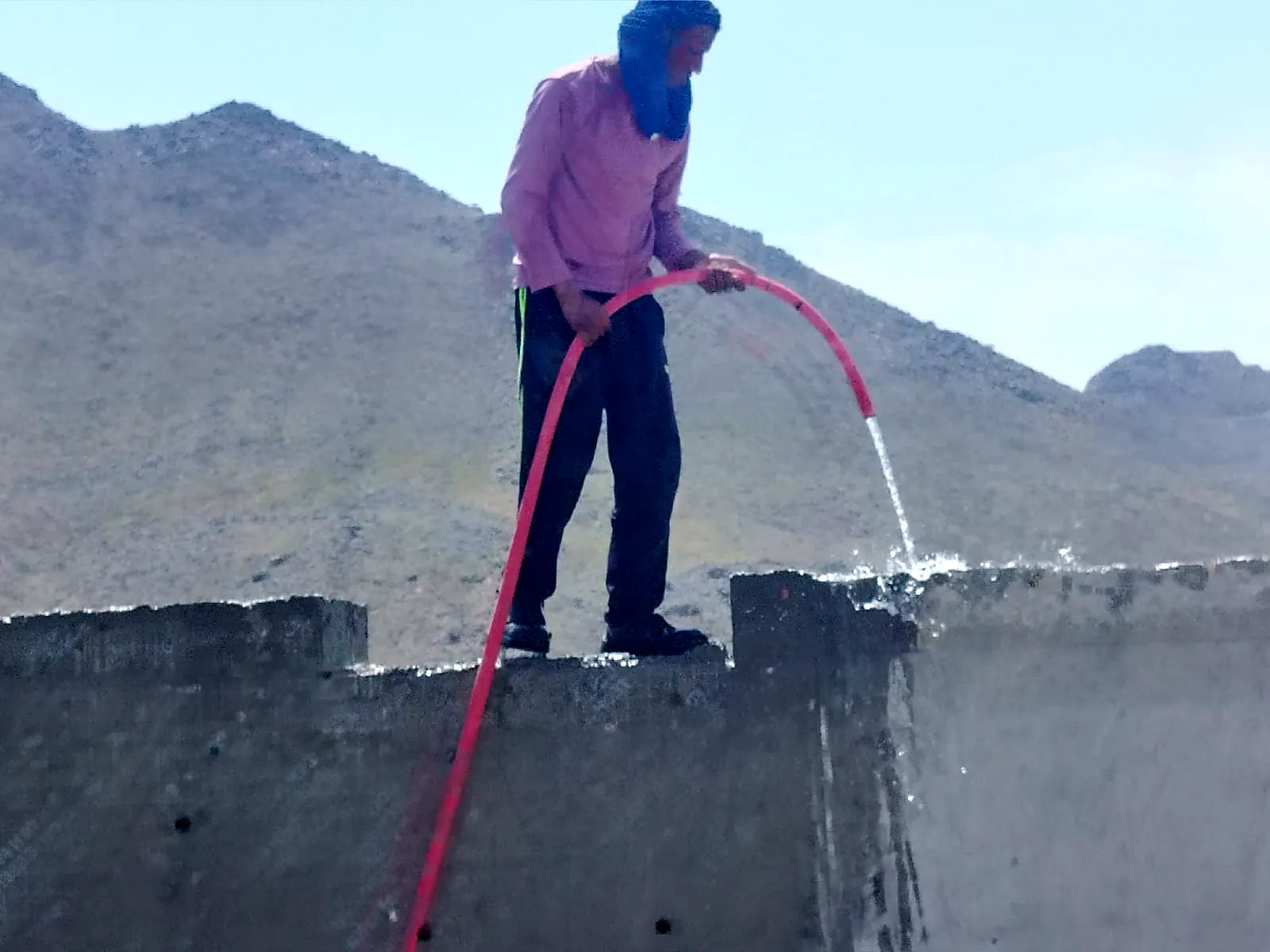 Curing a concrete parapet wall with a water hose against the mountains