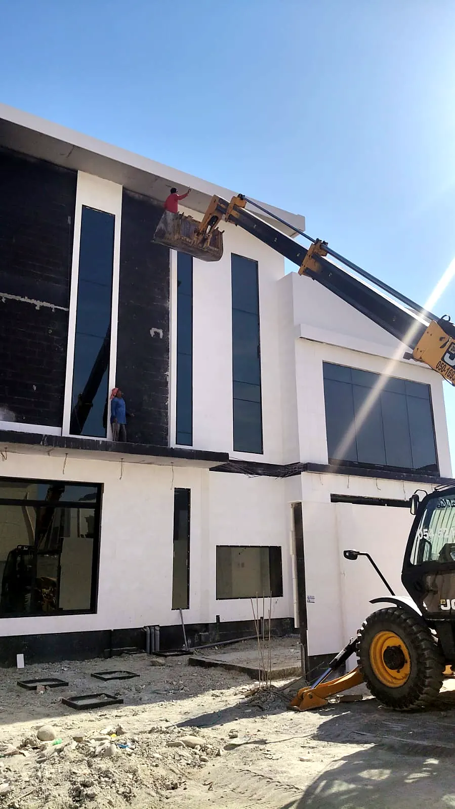 Contemporary villa with black glazing panels and an angled roof edge during façade installation