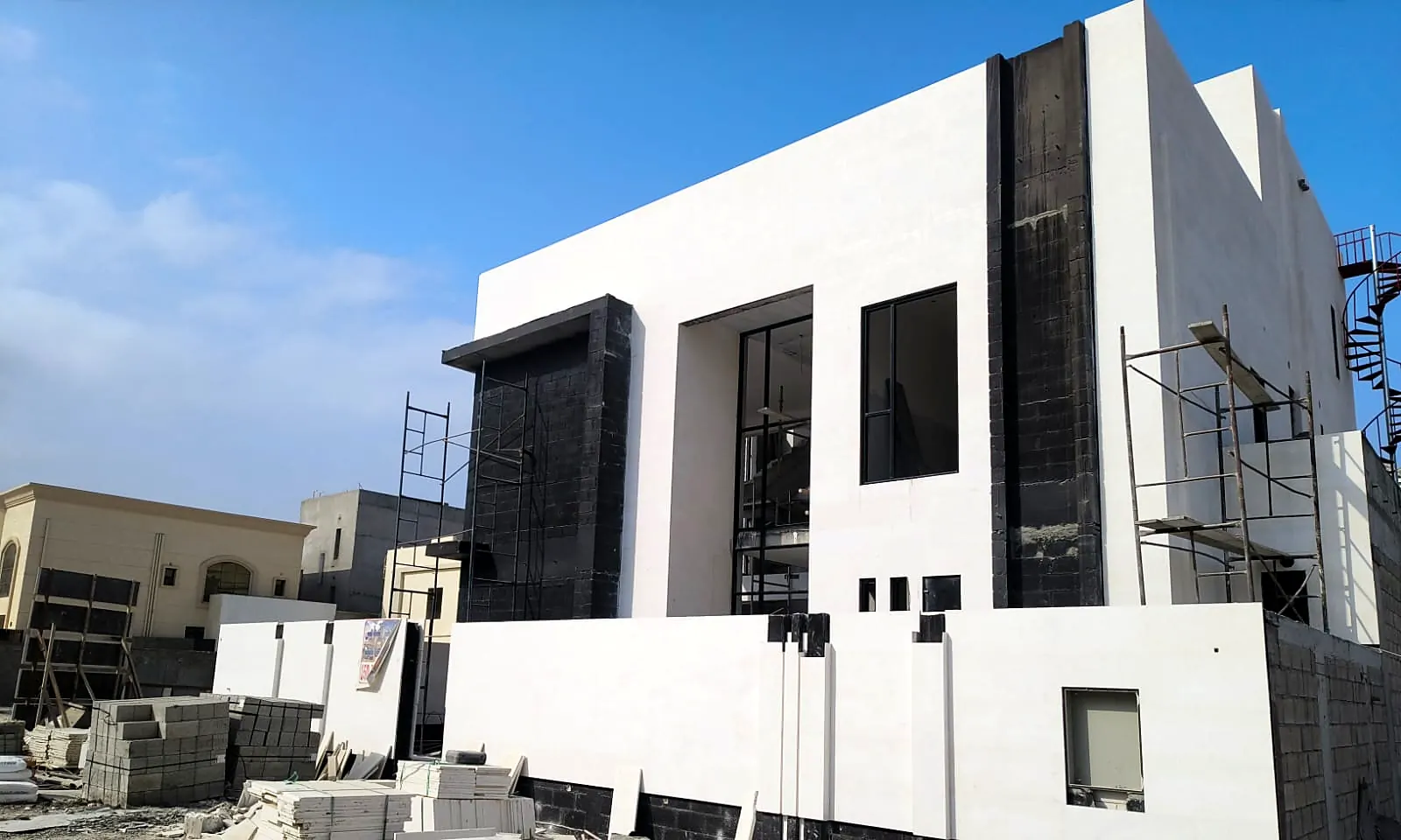Two-storey contemporary villa in Khorfakkan with white stone façade, black stone feature panels and a new boundary wall