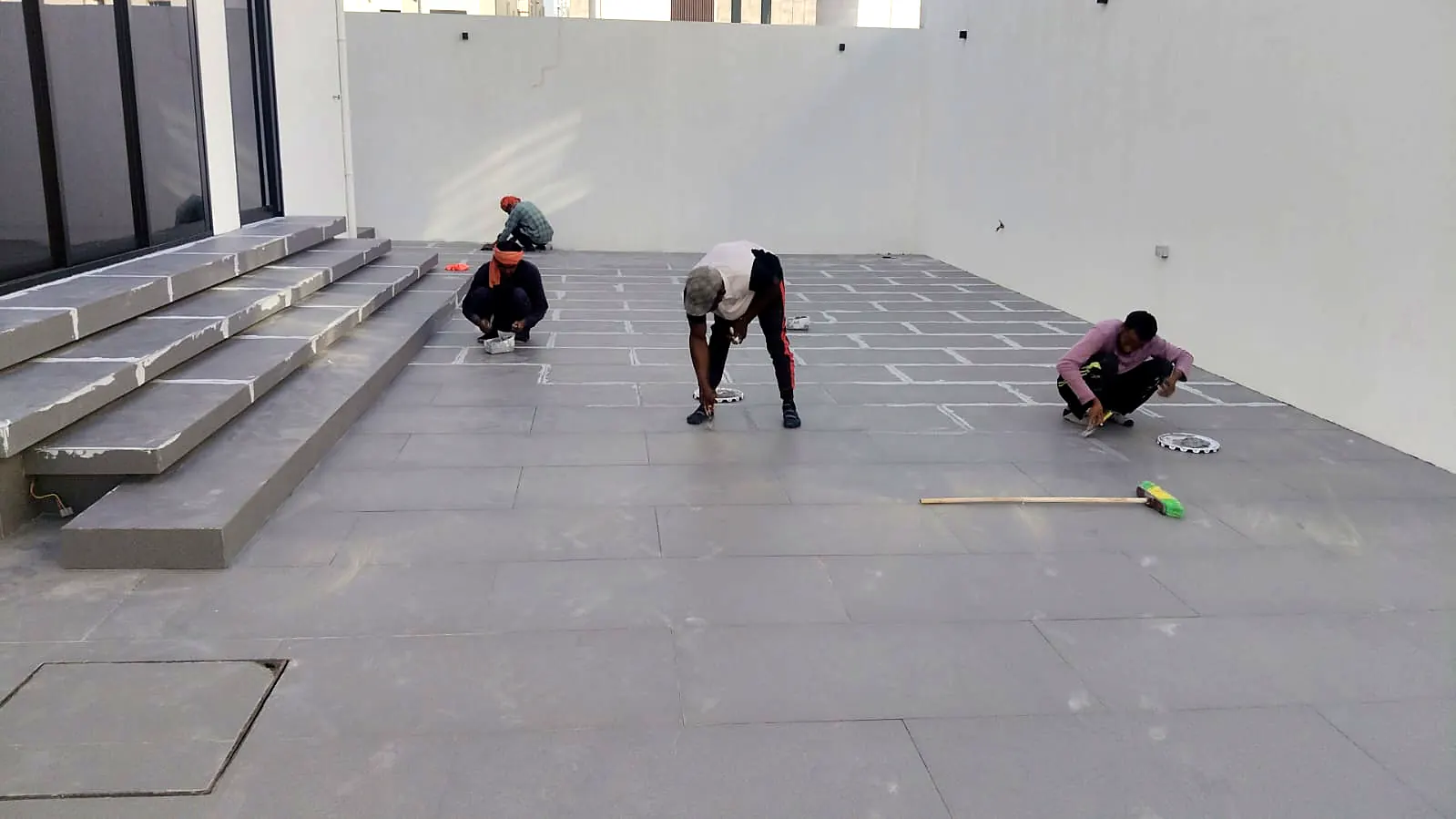 Floor tiling being set out in a large hall beside stone steps