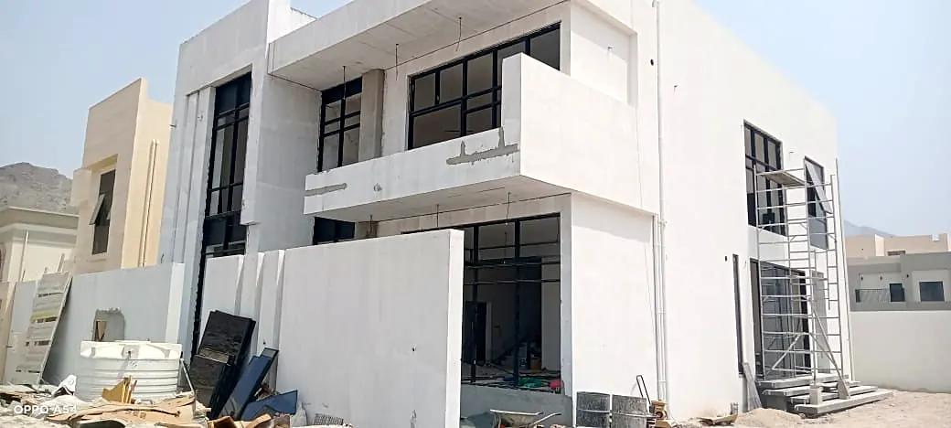 White modern villa with glazed balconies and framed openings as façade works near completion