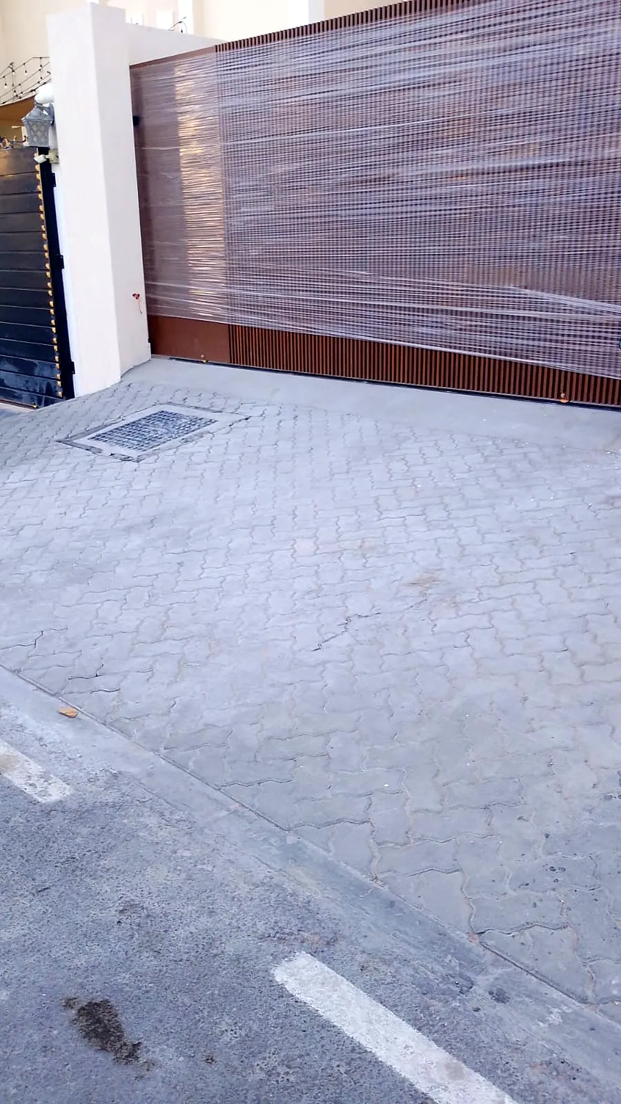 Paved driveway with drainage grating beside a timber-look gate