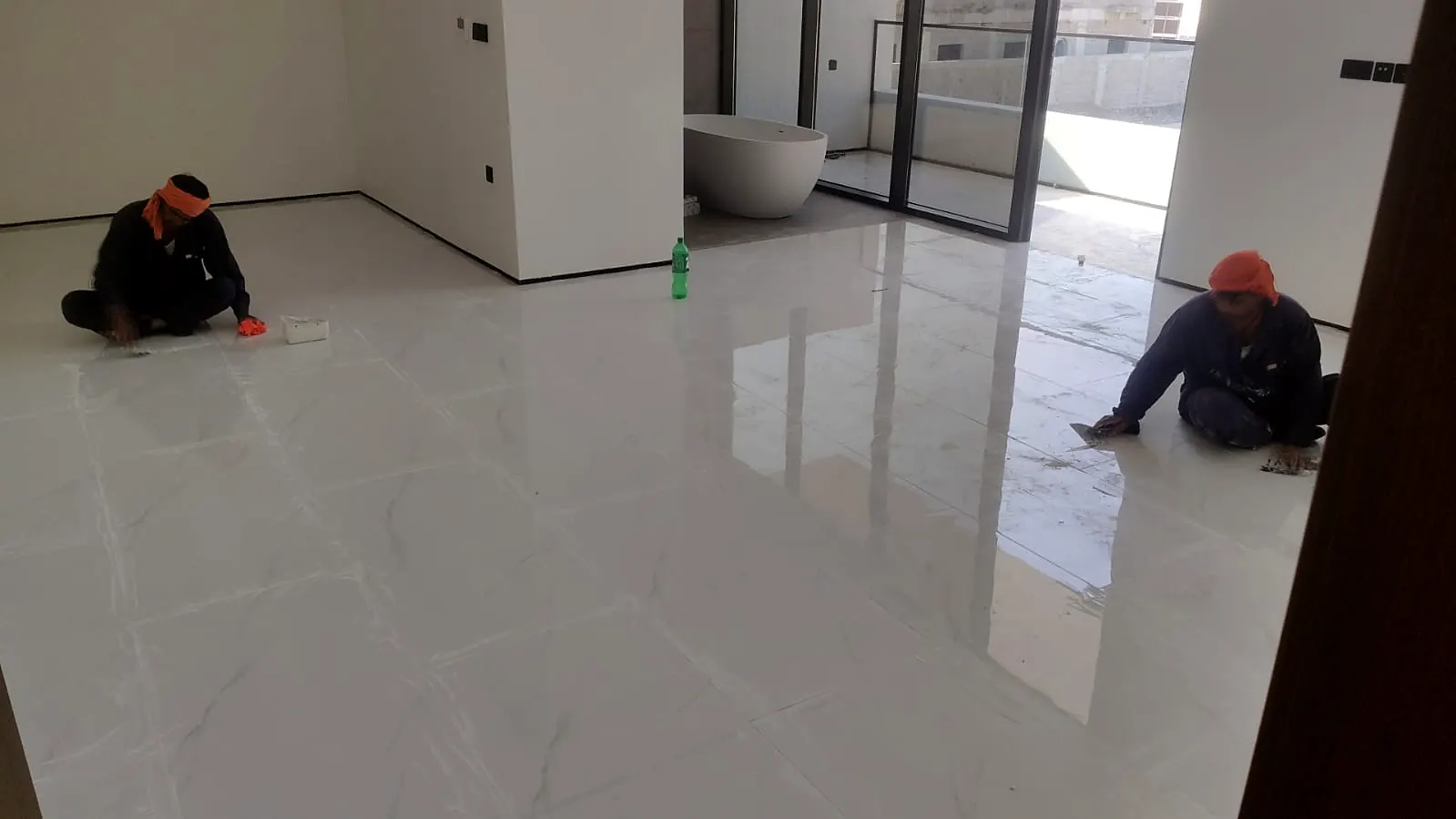 Large-format polished floor tiles in a bright villa interior with a freestanding bathtub