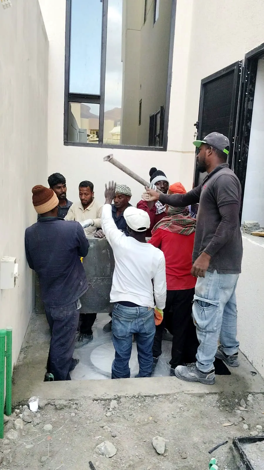 Site team working together to position heavy material in a villa side passage