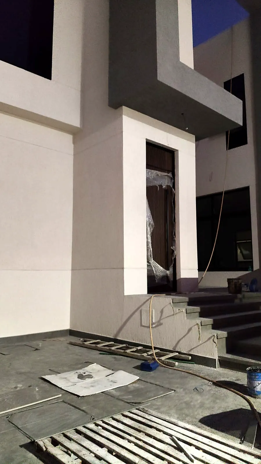 Villa entrance with grey frame surround and dark stone steps under construction