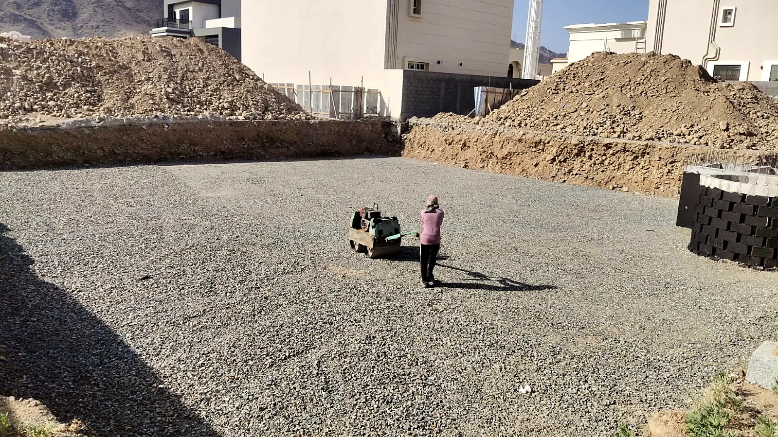 Excavated villa plot being levelled and compacted with a plate compactor