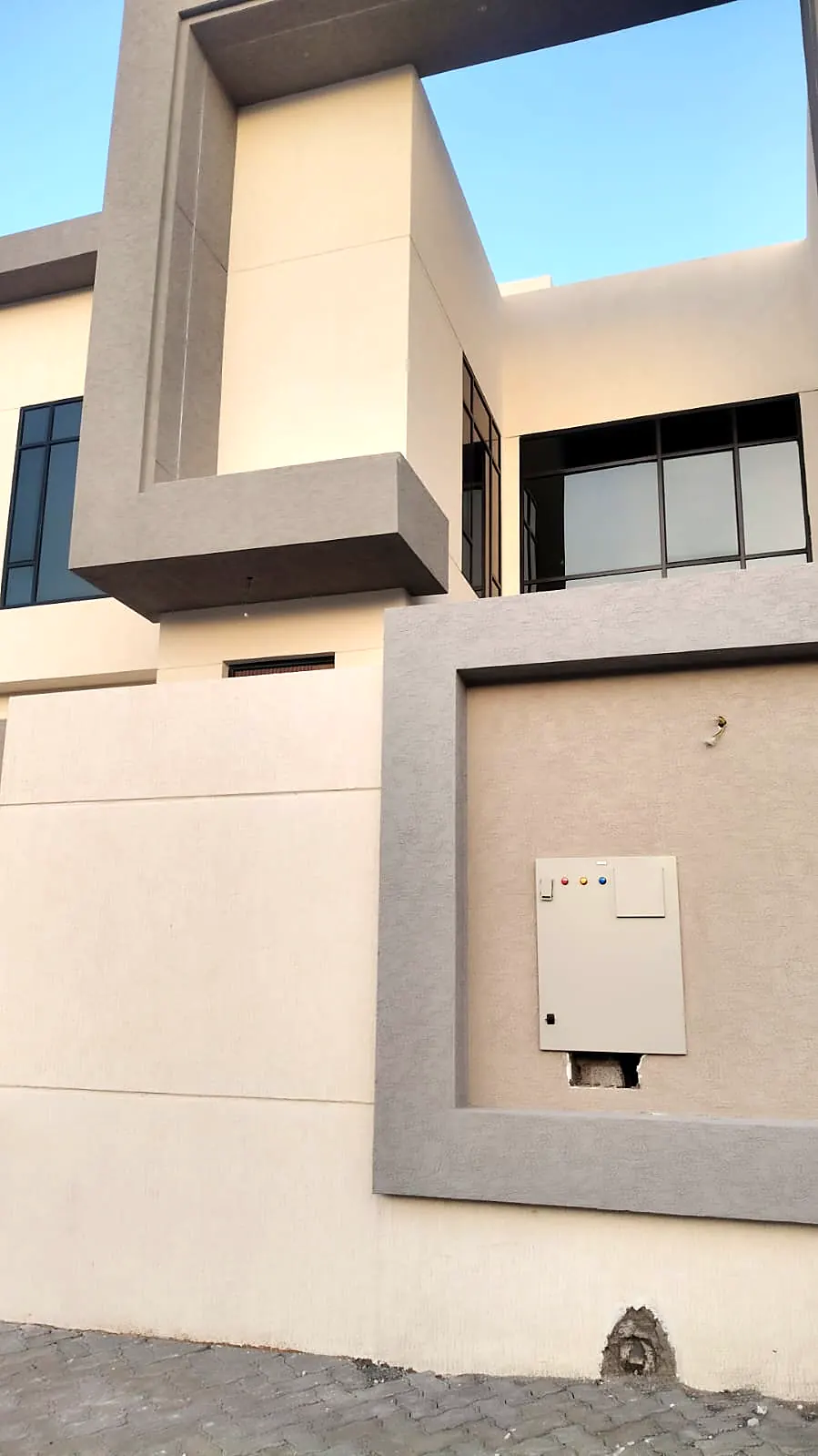 Grey stone frame and boundary wall detail on a beige villa façade
