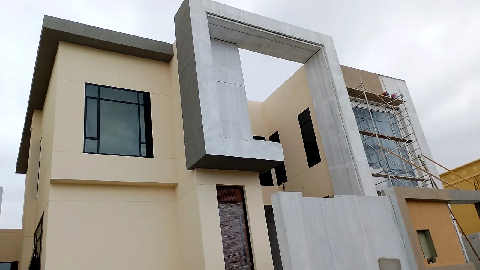 Villa with beige façade and a grey stone portal frame around the upper-floor window