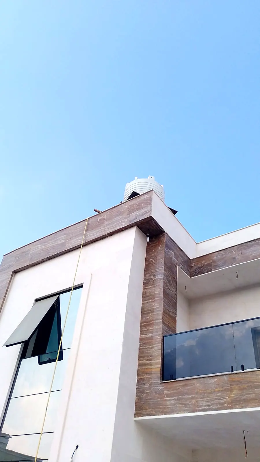 Upper floor of a villa with timber-effect cladding and a glass balcony balustrade