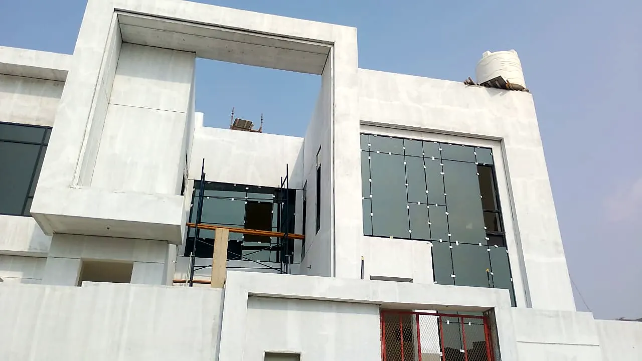 White villa with a large rectangular portal frame and glass balcony balustrade